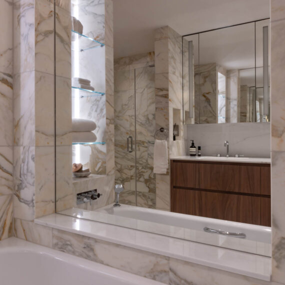 Luxury bathroom design in Hampstead with natural marble, bespoke walnut vanity and illuminated shelving